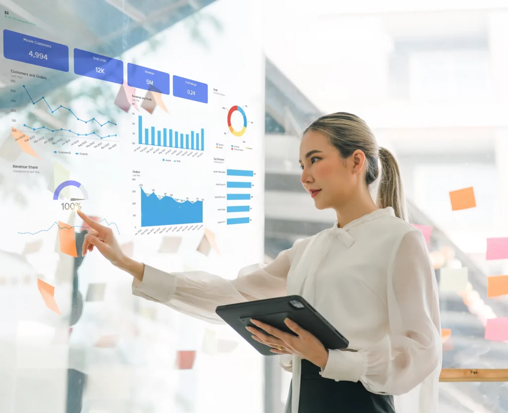 Businesswoman analyzing sales data and charts on a transparent screen in a modern office.