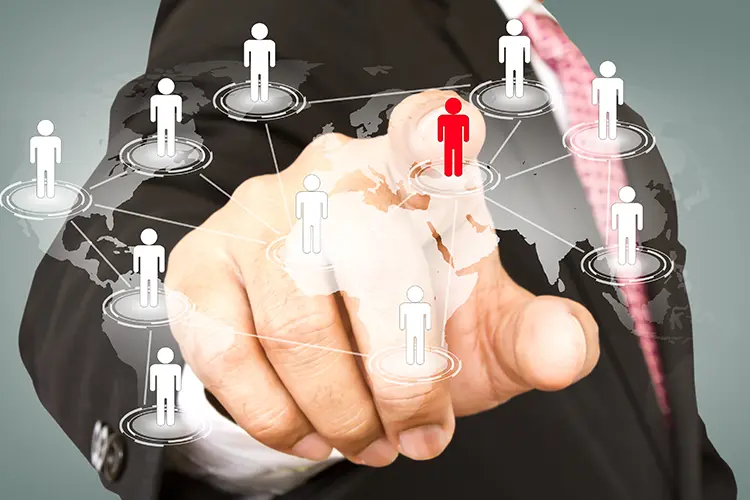 A person in a suit points at a digital map with interconnected icons representing people, highlighting a central red figure.
